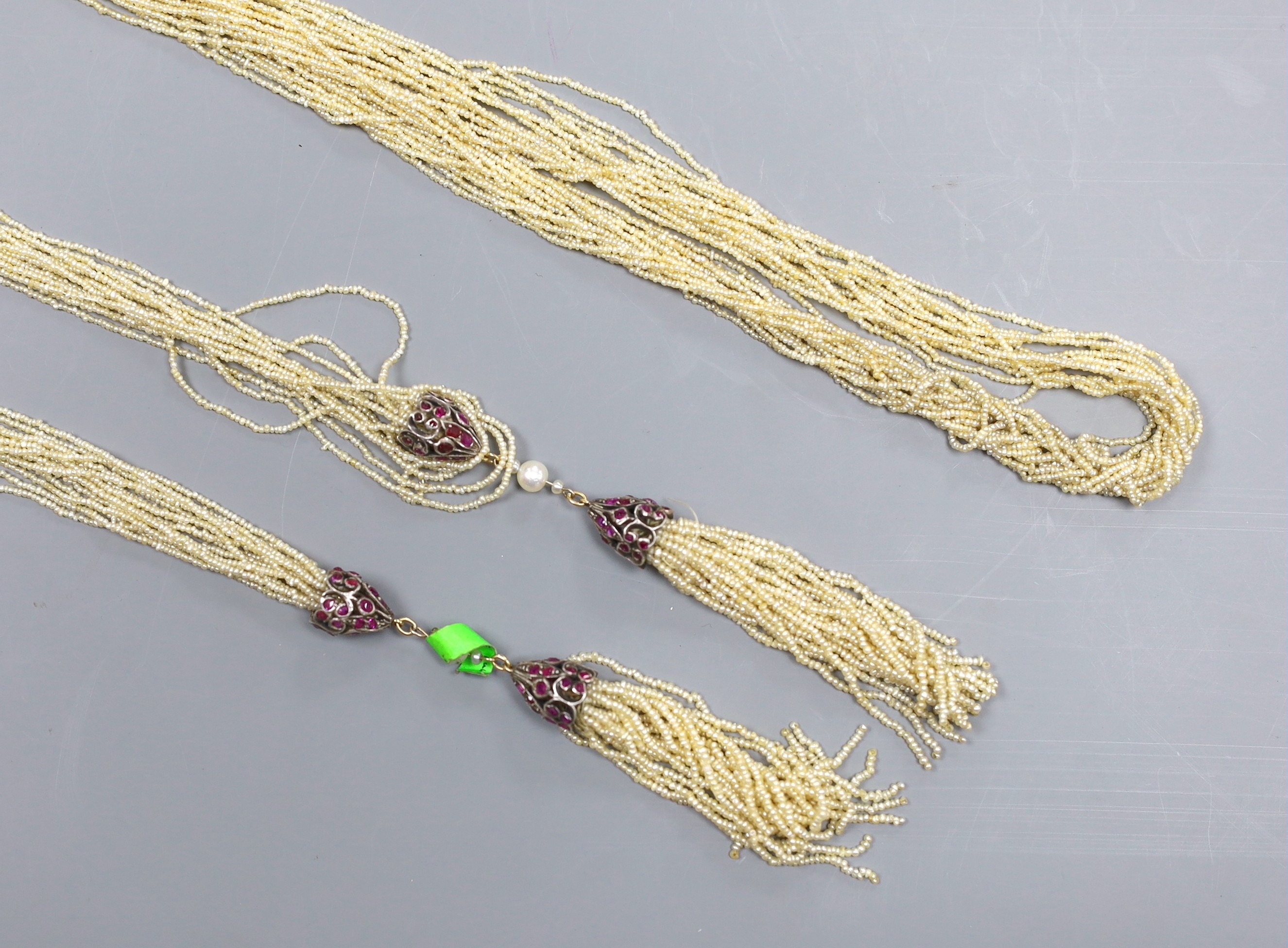 An Indian multi-strand seed pearl sautoir necklace, with ruby set white metal terminals, length 130cm